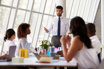 Hispanic Businessman Leading Meeting At Boardroom Table
