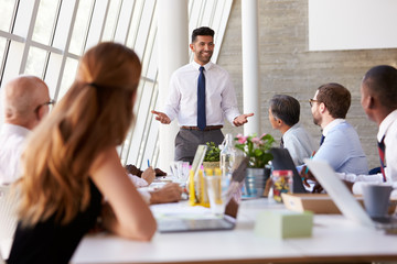 Hispanic Businessman Leading Meeting At Boardroom Table