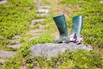 A pair of muddy rain boots used for working in the mud and two working gloves on a rock. Location: Northern Sweden.
