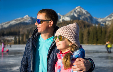 Father with daughter enjoying winter vacations over  mountains background