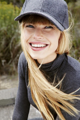 Joyful young blond model in gray cap, portrait