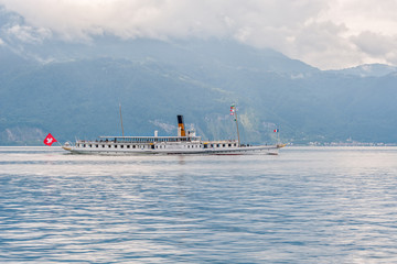 Steamboat crossing a lake between mountains in Switzerland.