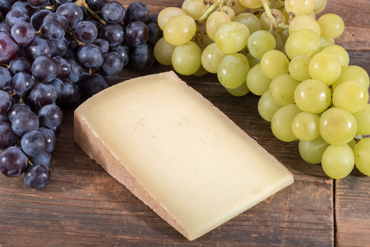 French comté cheese with black and white grapes