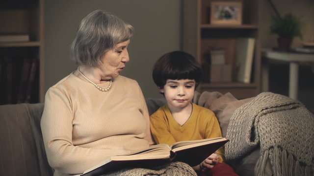 Grandmother reading a book to her lovely little grandson 