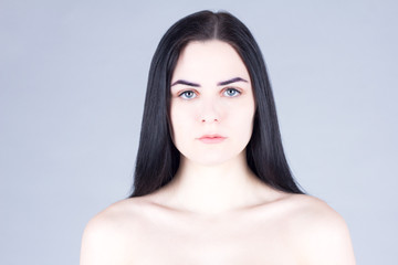 Smooth face of a woman with dark hair, gray eyes and fair skin