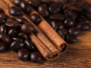 Coffee beans with cinnamon and anise on wooden table