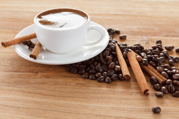 Coffee cup and beans, cinnamon sticks, anise on wooden table