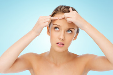 Naklejka premium young woman squeezing pimple on her face