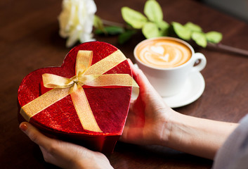 close up of hands holding heart shaped gift box