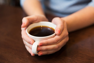close up of woman holding hot black coffee cup
