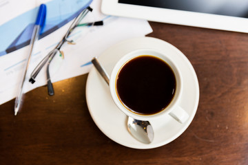close up of coffee, charts and tablet pc on table
