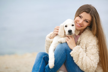 A young woman near the sea with a puppy Retriever