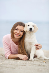 A young woman near the sea with a puppy Retriever