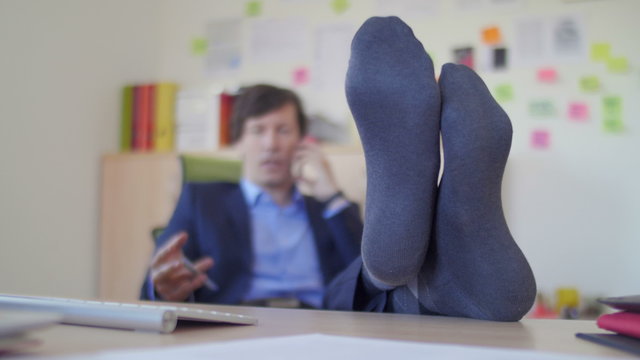 Business man talking over phone with feet on the desk