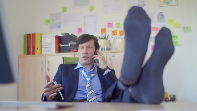 Business man talking over phone with feet on the desk