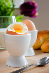 Fresh breakfast: Milk, egg and sweet bun on a wooden plate