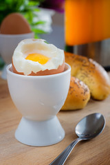 Fresh breakfast: Tea, egg and sweet bun on a wooden plate