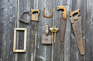 Rusty vintage carpenter tools and horseshoe hanged on wooden wall