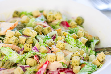 Bowl of Salad with Chicken, Bacon and Croutons on a White Wooden Background, Close-up