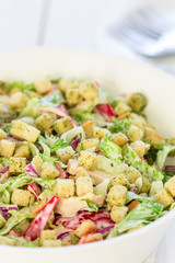 Bowl of Salad with Chicken, Bacon and Croutons on a White Wooden Background, Close-up