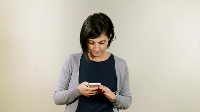Young woman using smartphone in studio. Smiling, laughing and snorting