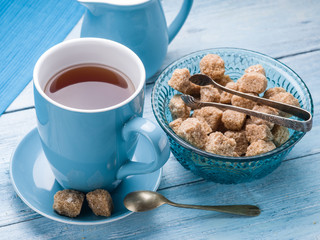 Cup of tea, milk jug and cane sugar cubes.