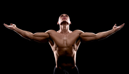 young handsome sexy bodybuilder looking up on a dark background