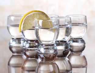 Glass cup with tequila and lemon on table
