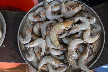свежие крупные королевские креветки в круглой посуде на рыбном рынке