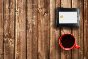 Wallet, credit card and coffee cup on wooden table