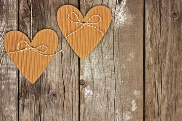 Two rustic heart shaped cardboard gift tags hanging against a vintage wood background