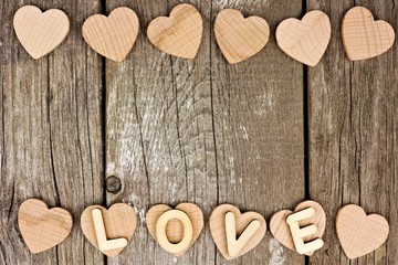 Valentines Day wooden hearts and LOVE letters forming a double border on rustic wood