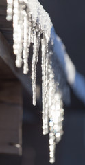 Long and dangerous icicles on a house roof - obrazy, fototapety, plakaty