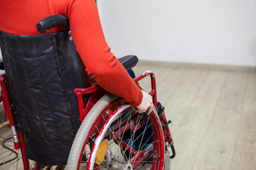Close-up cropped view of handicapped person sitting invalid wheelchair and holding wheel, copy space