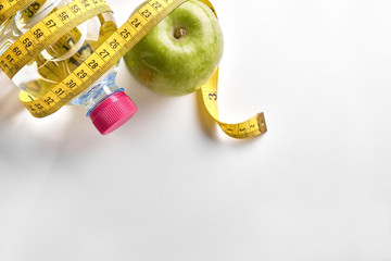 Measuring tape around a bottle of water and apple top