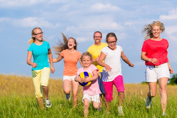 Family playing ball games on meadow