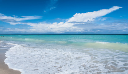 Beautiful blue sky holiday.  Varadero beach scene - getaway on a vacation beach in Cuba. Warm ocean waves gently lap against a Cuban beach. 