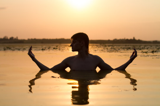 man meditate in water in rays of sun