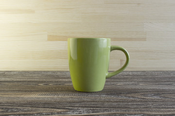 Green ceramic mug is in the center of a wooden background