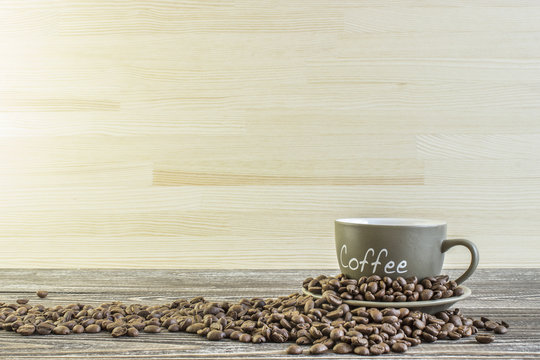 Fototapeta Cup of coffee  with beans standing on a wooden table