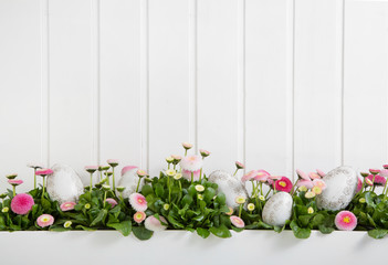 Oster Hintergrund aus Holz weiß mit rosaroten Gänseblümchen und Ostereier