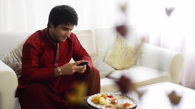 Pan shot of a man text messaging on a mobile phone at Raksha Bhandan festival