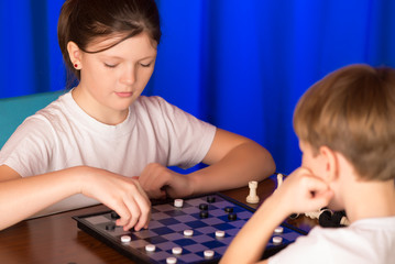 Children boy and girl playing a board game called Checkers