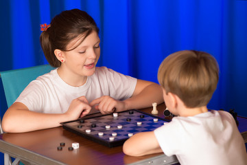 Children boy and girl playing a board game called Checkers