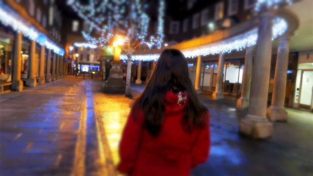 Young Woman Walking through Christmas Decorated City