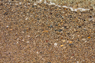 Colored pebbles on the beach and sea wave