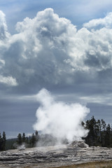 Steam and black clouds over Old Faithful geyser, Yellowstone, Wyoming.