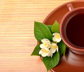 Tea on the ceramic cup with jasmine flower on the wood
