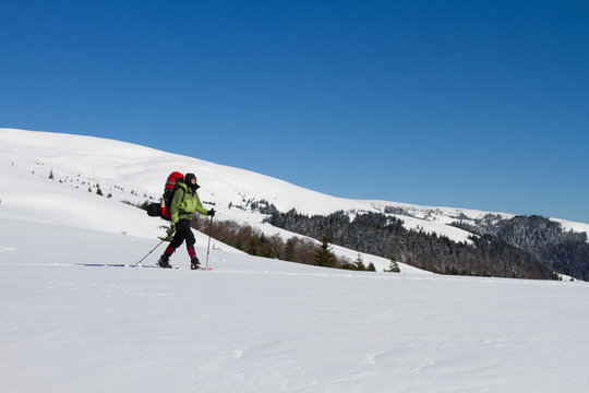 Winter hiking in the mountains on snowshoes with a backpack and tent.