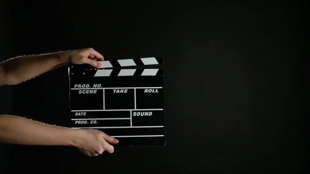 Hands with movie clapper board, on black, slow motion